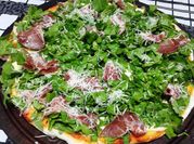 Una foto de pizza con rúcula y jamón crudo