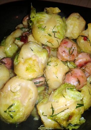 A picture of brussels sprouts with sausage and dill.