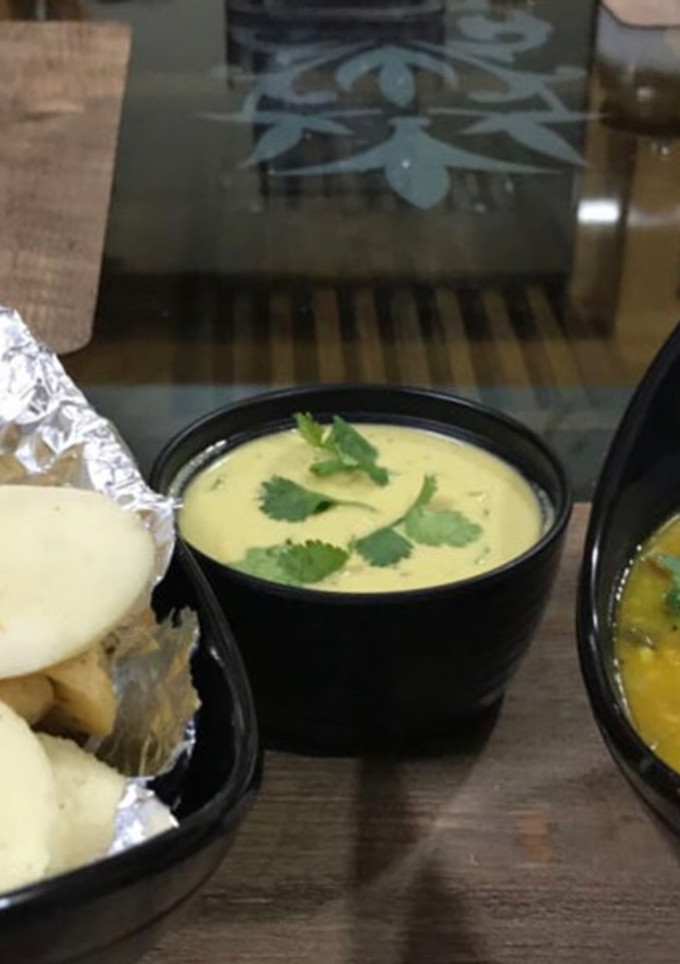 A picture of Soft Rava Idli with sambar and coconut chutney.