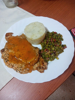 Una foto de Chuletas de cerdo adobadas con puré de papas, guisantes y salsa
