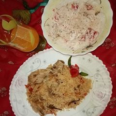 A picture of Mughlai pulao Biryani with Raita salad And orange juice.