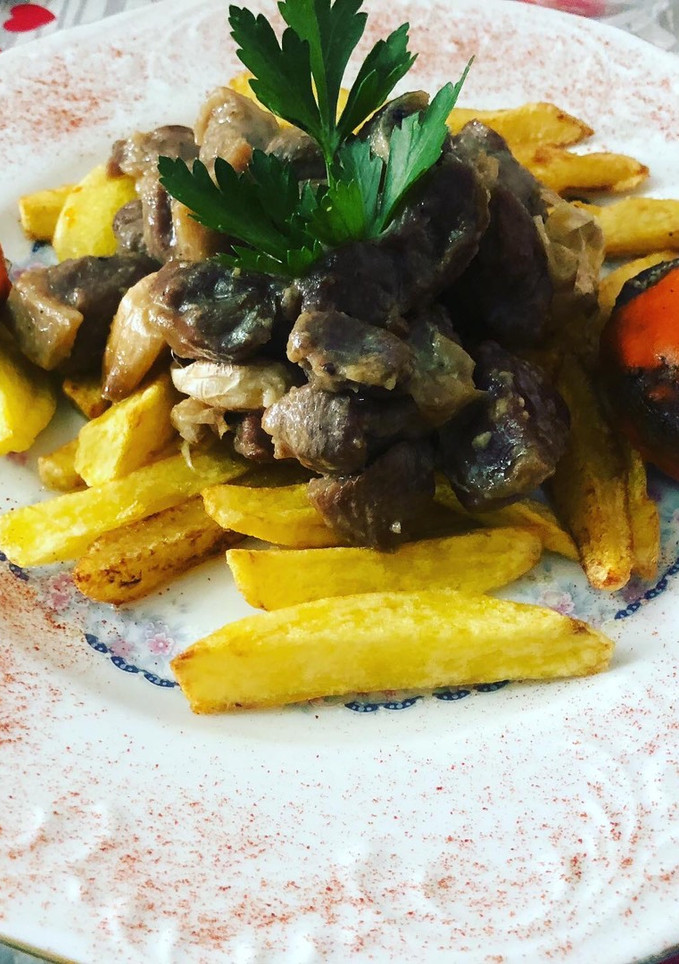 Una foto de Cordero al ajillo con patatas fritas y champiñones rellenos