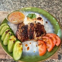 A picture of Cambodian grilled chicken over rice.
