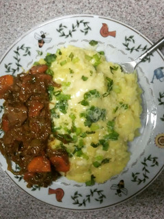 A picture of cheesed mash potatoes topped with spring onions & chicken liver stew.