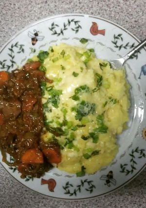 A picture of cheesed mash potatoes topped with spring onions & chicken liver stew.