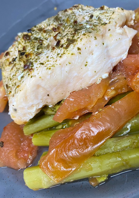 Una foto de Salmón con espárragos verdes y tomate al Lékué
