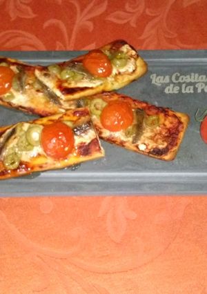 Una foto de Coca de anchoas, aceitunas y tomatitos cherry