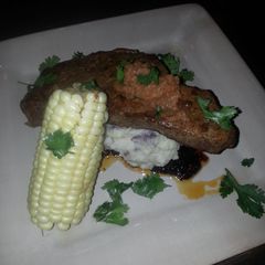 A picture of Seard NY strip with pan sauce garlic mash potatoes and corn on the cob.