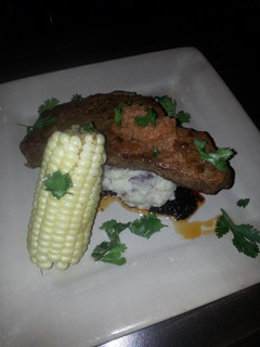 A picture of Seard NY strip with pan sauce garlic mash potatoes and corn on the cob.