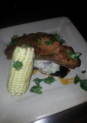 A picture of Seard NY strip with pan sauce garlic mash potatoes and corn on the cob.