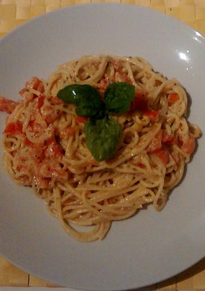 A picture of Pasta with pesto, ricotta cheese and tomato.