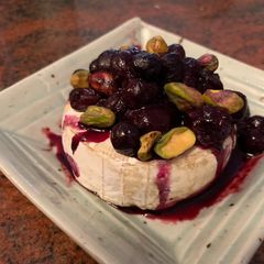 A picture of Brie with pistachios and blueberries.