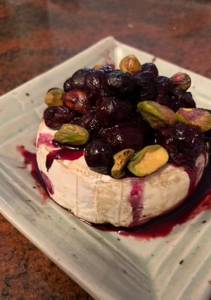 A picture of Brie with pistachios and blueberries.
