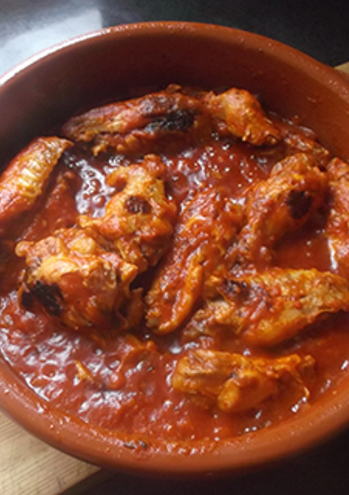 Una foto de Alitas de pollo con tomate y cebolla