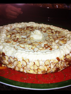 A picture of carrot and almond cake with cream cheese frosting.
