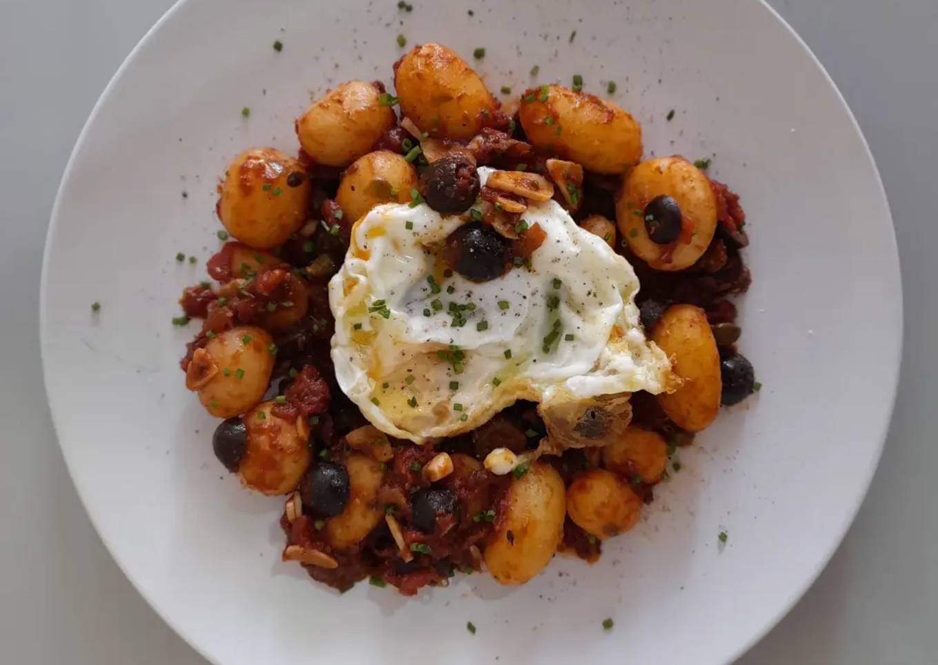 Patatas a la puttanesca con huevo frito