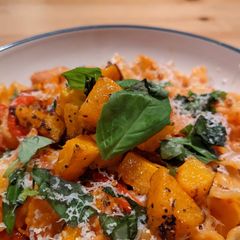 A picture of Mafaldine pasta with butternut squash, peppers, and bacon.