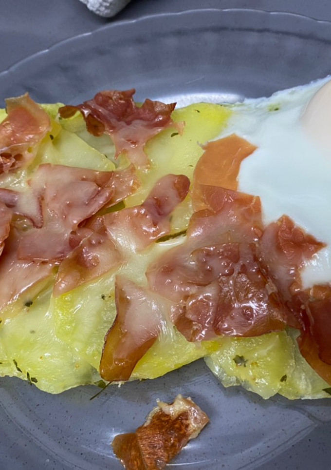 Una foto de Huevo con patatas, jamón serrano y queso rallado en estuche Lékué