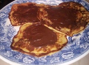 Una foto de Tortitas de banano cubiertas de chocolate. (panqueques)
