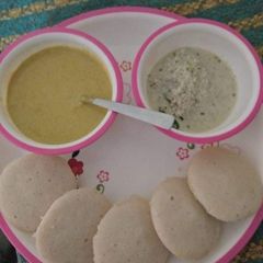 A picture of Idlis with coconut chutney and peanut chutney.