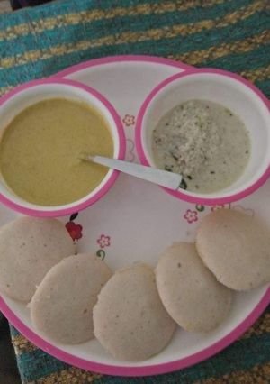 A picture of Idlis with coconut chutney and peanut chutney.