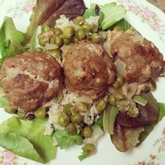 A picture of Turkey Meatballs w/ brown rice & peas over a bed of mixed greens.