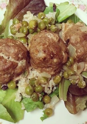 A picture of Turkey Meatballs w/ brown rice & peas over a bed of mixed greens.