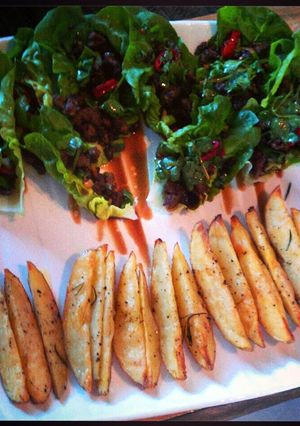 A picture of Chilli beef in lettuce cups with roast potato wedges.