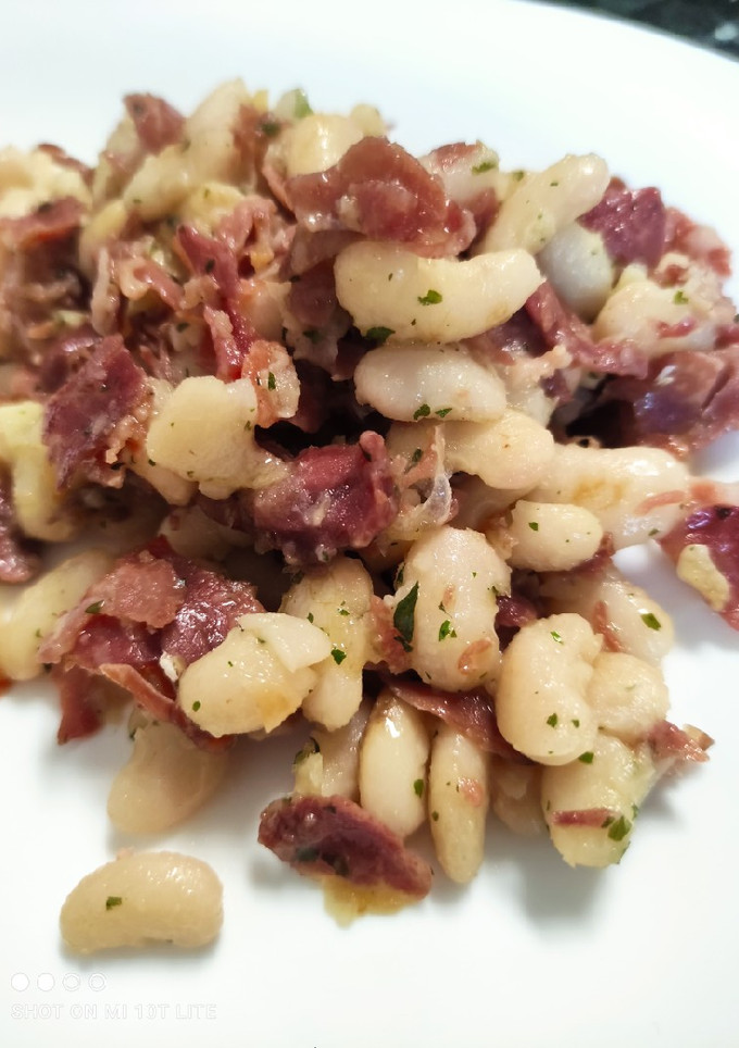 Una foto de Alubias con jamón serrano, ajo y perejil 🌱