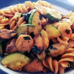 A picture of Fusilli pasta with chicken, mushroom and zucchini.