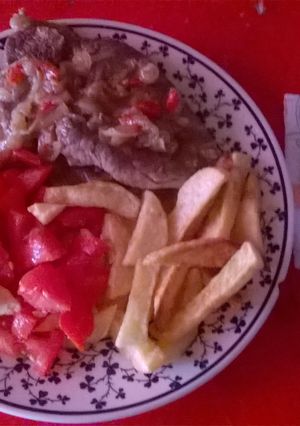 Una foto de Bifes con cebolla morrón y papas fritas
