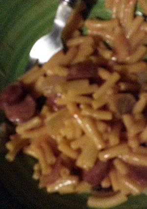 A picture of Mac & Cheese with fried onions and smocked sausage.