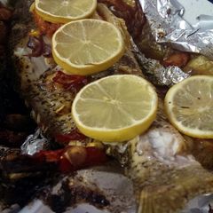A picture of Baked red snapper with lemon and tomato.