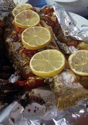 A picture of Baked red snapper with lemon and tomato.