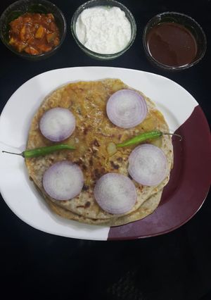 A picture of Punjabi Aloo paratha, tamarind chutney, yoghurt and pickle.