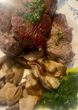 A picture of Ribeye Steak with Porcini Mushrooms and Pesto Sauce.