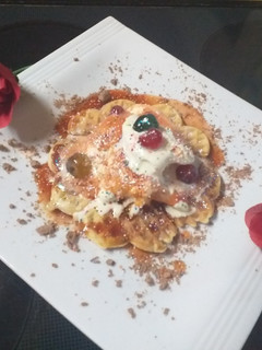 A picture of Waffles and ice cream with berry sauce and cator sugar.