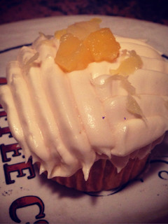 A picture of Pineapple & Coconut Cupcake W/ Coconut Frosting & Pineapple Shredding On Top.