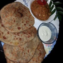 A picture of Aloo paratha with tomato garlic chutney and curd.