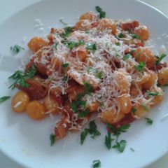 A picture of Gnocchi with red pepper and prosciutto.