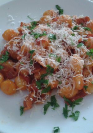 A picture of Gnocchi with red pepper and prosciutto.