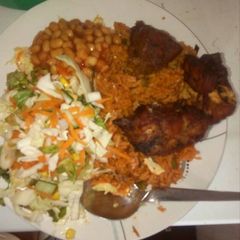 A picture of Jollof rice with salad and chicken,.