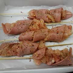 A picture of chicken skewers with turkey bacon.