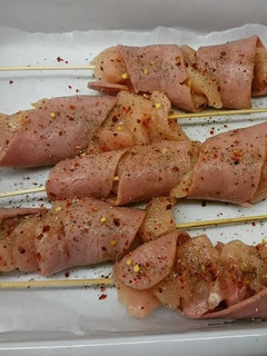 A picture of chicken skewers with turkey bacon.