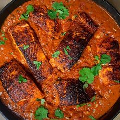 A picture of Blackened Cajun Salmon in Creamy Fire Roasted Tomato Coconut Sauce.