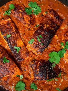 A picture of Blackened Cajun Salmon in Creamy Fire Roasted Tomato Coconut Sauce.