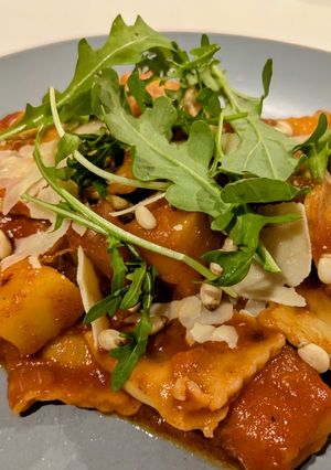 A picture of Ravioli and pumpkin in tomato sauce.