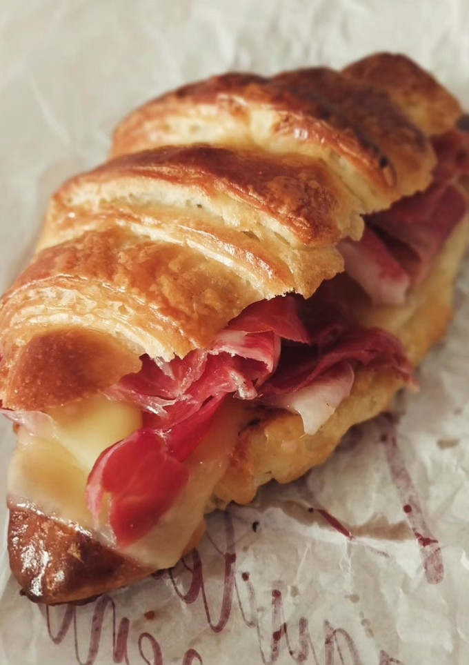 Una foto de Croissant (v4) relleno de jamón serrano y queso fundido