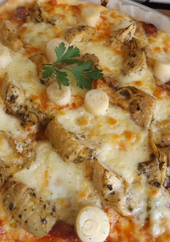 Una foto de Pizza casera con quesos, alcachofas, palmitos y salchichón ibérico