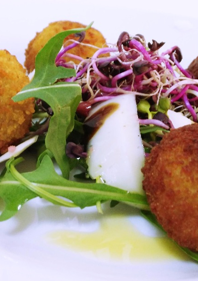 Una foto de Ensalada templada de rúcula y germinados con croquetas de ancas al ajo negro